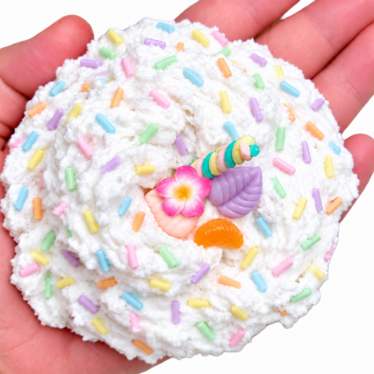 Piña Colada snow fizz slime held in a hand with pastel sprinkles and tropical charms
