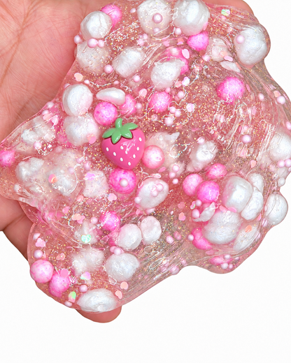 Strawberry Sparkling Soda clear slime held in a hand showing glitter and crunchy foam beads